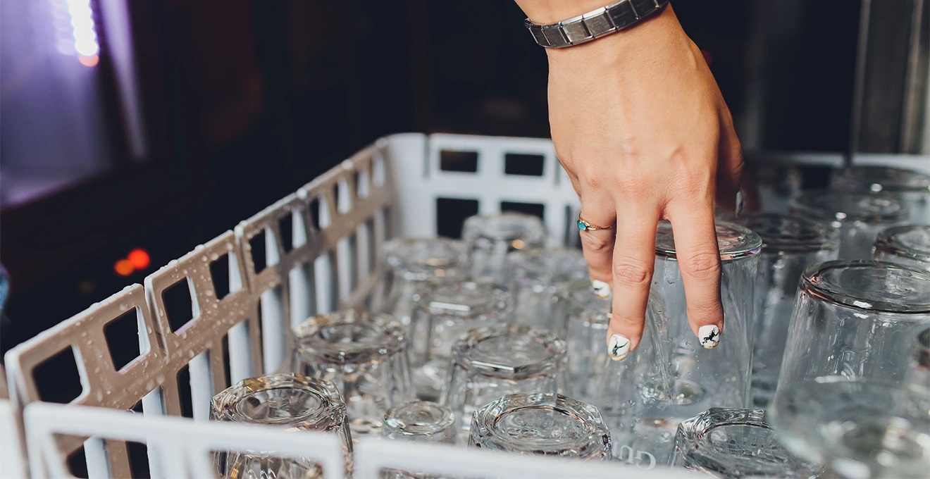 Une personne rince un verre à bière pied à l'eau claire au-dessus d'un évier de cuisine.